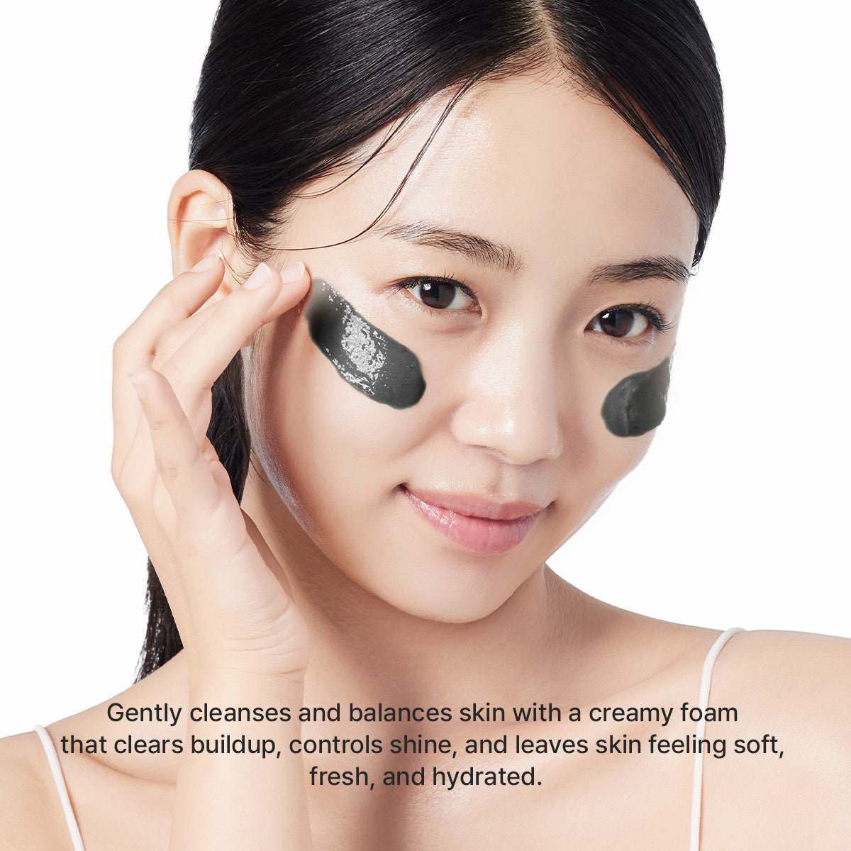Woman applying Arencia Black Tea Rice Mochi Cleanser to her cheeks, demonstrating the black cleansing mask texture.